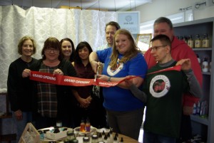 Sara Hafner, owner of Mooseberry Soap Co., cuts grand opening ribbon with friends and family by her side.